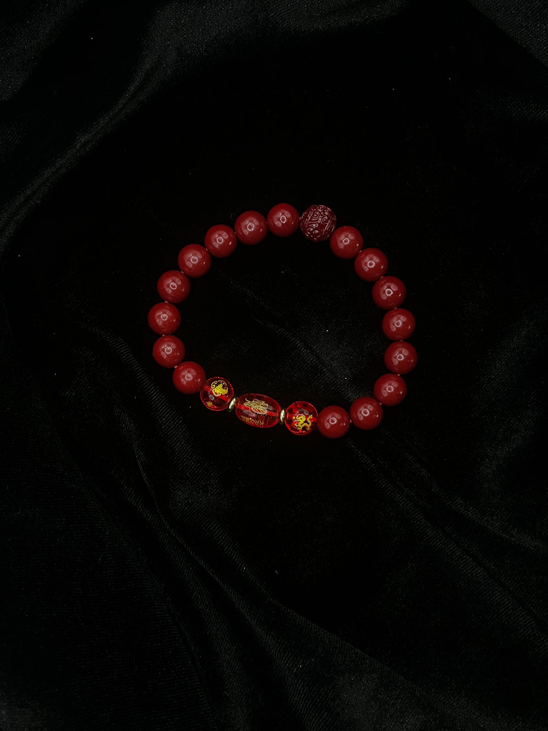 Red beaded bracelet on a black textured fabric background
